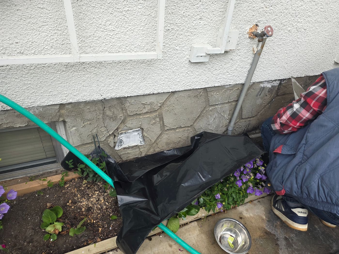 Cracked and flaking parging on a Calgary home's concrete foundation wall before repair