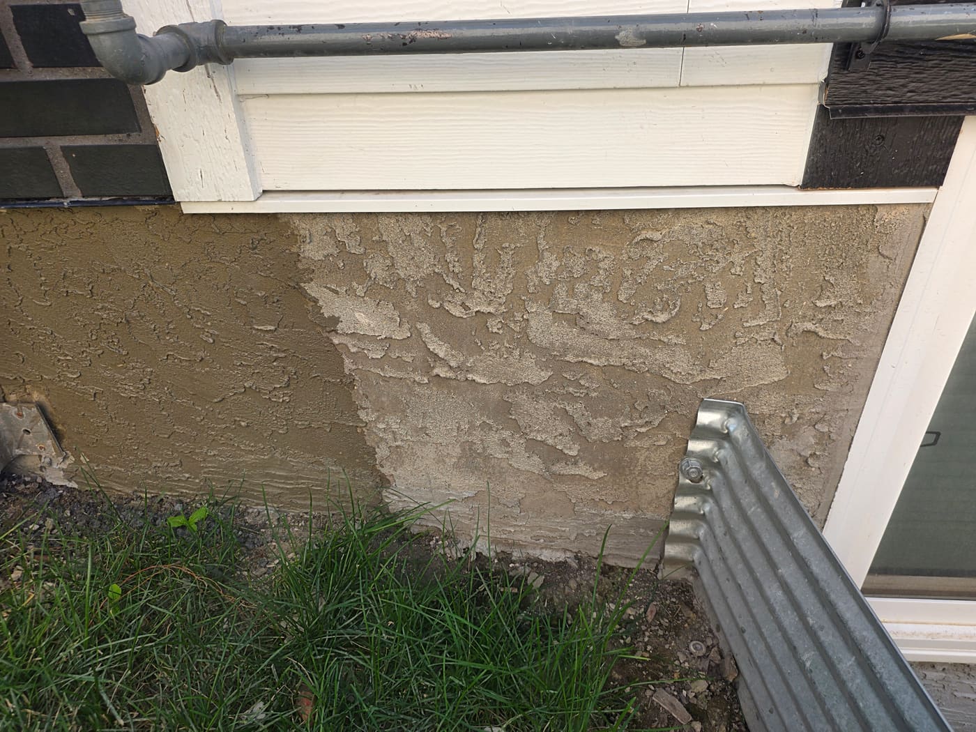 Peeling, chalky parging on a Calgary foundation wall before rejuvenation