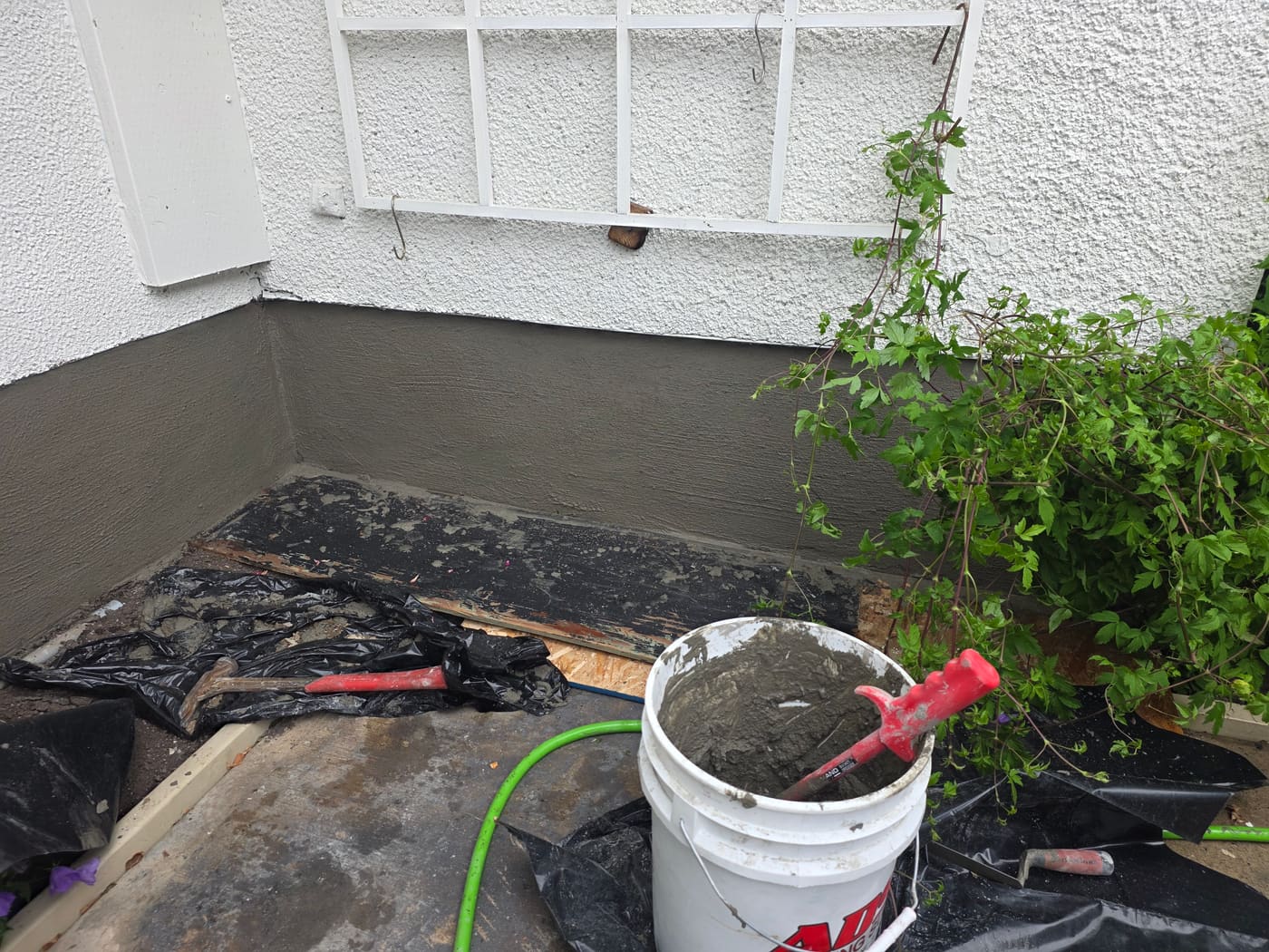 Smooth grey parging coat being applied by hand to a foundation wall in Calgary